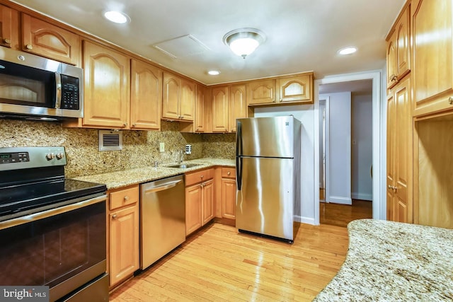 kitchen featuring stainless steel appliances, light wood-style flooring, decorative backsplash, light stone counters, and recessed lighting