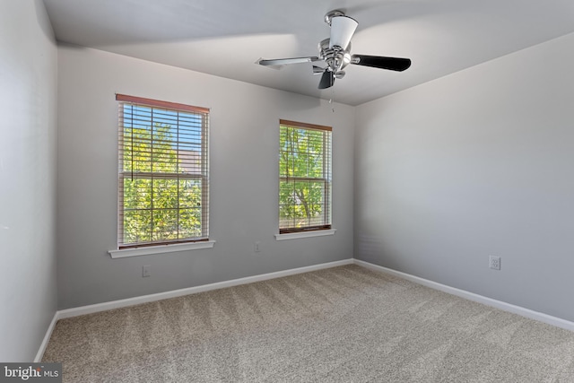 carpeted spare room featuring baseboards and ceiling fan