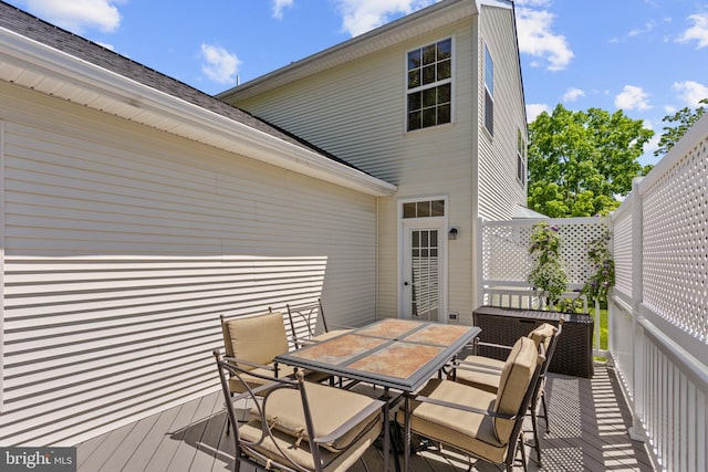 wooden terrace with outdoor dining space and fence