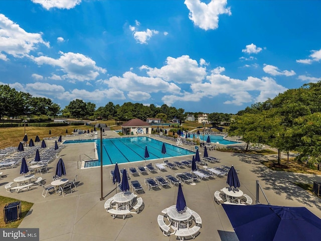 community pool featuring a patio area and view of scattered trees