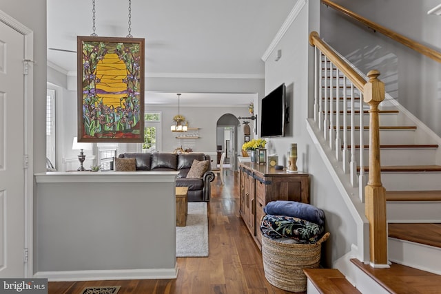 living room featuring ornamental molding, arched walkways, hardwood / wood-style floors, and stairs