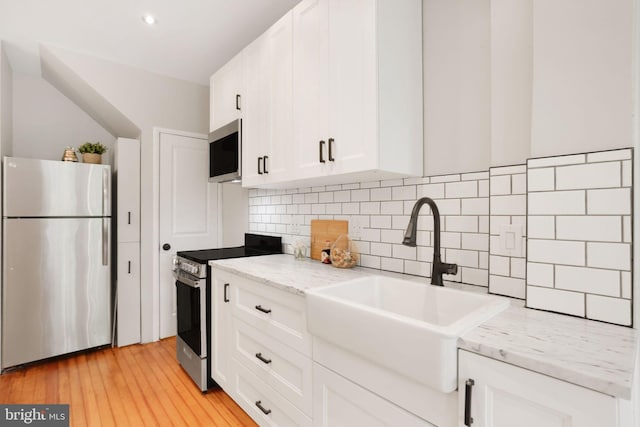 2420 2nd St NE, Washington, DC 20002 - kitchen featuring stainless steel appliances, a sink, white cabinets, decorative backsplash, and light wood-style flooring