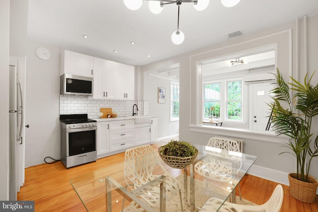 2420 2nd St NE, Washington, DC 20002 - kitchen featuring appliances with stainless steel finishes, light wood-style flooring, white cabinetry, tasteful backsplash, and recessed lighting