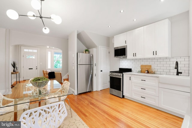 2420 2nd St NE, Washington, DC 20002 - kitchen featuring stainless steel appliances, a sink, light wood-type flooring, backsplash, and white cabinetry