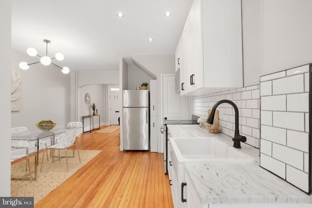 2420 2nd St NE, Washington, DC 20002 - kitchen featuring freestanding refrigerator, a sink, white cabinets, a chandelier, and light wood finished floors