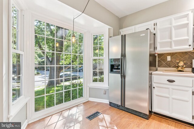 1509 Carlyle Dr Unit 152, Crofton, MD 21114 - kitchen featuring stainless steel fridge with ice dispenser, white cabinetry, backsplash, light wood finished floors, and decorative light fixtures