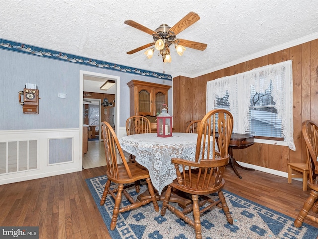 dining area with ceiling fan, hardwood / wood-style flooring, a textured ceiling, and crown molding