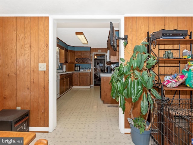 kitchen with light floors, brown cabinetry, dishwasher, white microwave, and light countertops