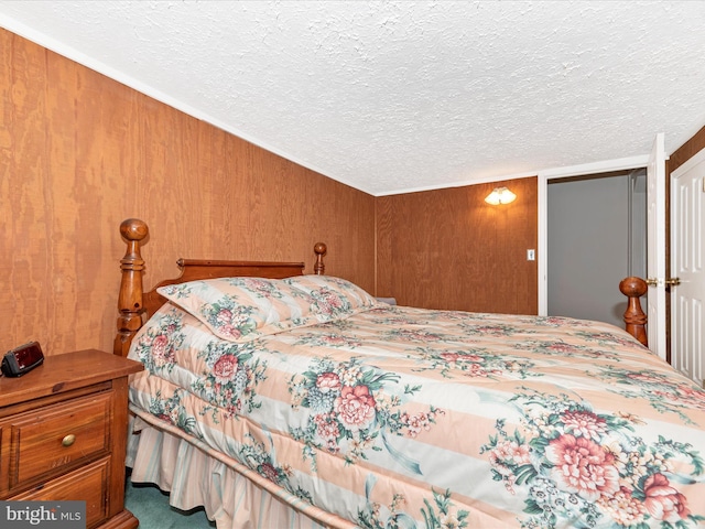 bedroom featuring a textured ceiling and wooden walls
