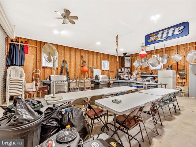 miscellaneous room featuring wood walls, a ceiling fan, concrete flooring, and healthy amount of natural light