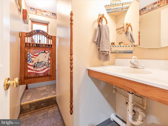 bathroom with stone tile flooring, baseboards, and a sink