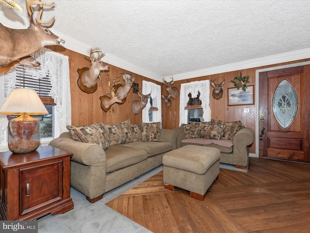 living room with ornamental molding, wood walls, a textured ceiling, and wood finished floors