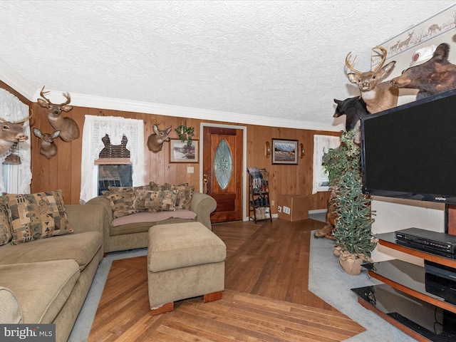 living room featuring crown molding, hardwood / wood-style flooring, wooden walls, and a textured ceiling
