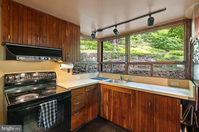 kitchen featuring electric range, under cabinet range hood, a sink, light countertops, and rail lighting
