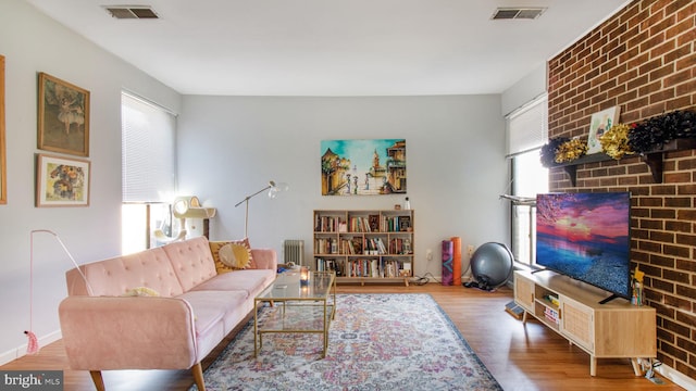 living area with plenty of natural light, wood finished floors, and radiator heating unit