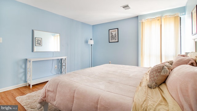 bedroom with wood finished floors, baseboards, and multiple windows