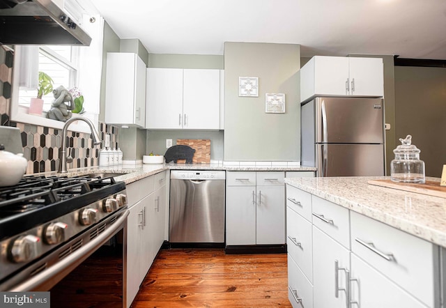 3211 Leverton Ave, Baltimore, MD 21224 - kitchen featuring stainless steel appliances, under cabinet range hood, wood finished floors, and white cabinets
