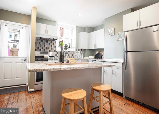 3211 Leverton Ave, Baltimore, MD 21224 - kitchen featuring appliances with stainless steel finishes, under cabinet range hood, a breakfast bar, light wood-style flooring, and recessed lighting