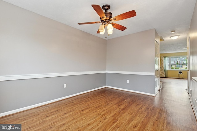 spare room with wood finished floors, baseboards, and ceiling fan