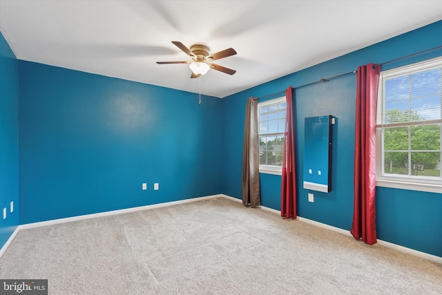 empty room featuring plenty of natural light, a ceiling fan, and carpet