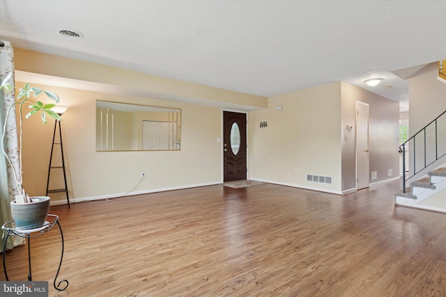 unfurnished living room featuring wood finished floors, stairway, and baseboards