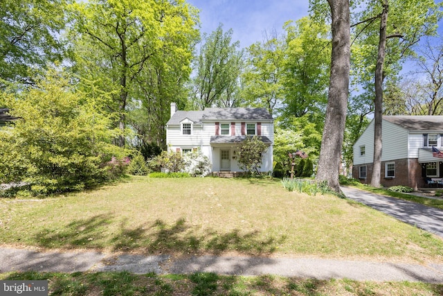 traditional-style home with a chimney and a front yard