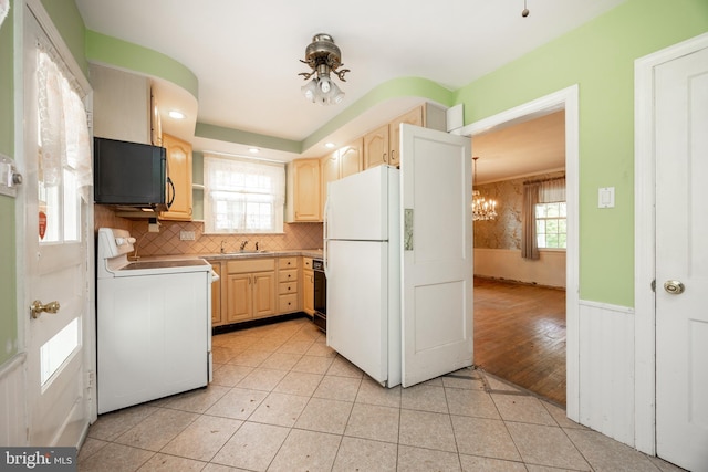 kitchen featuring range, freestanding refrigerator, light brown cabinetry, a sink, and a chandelier