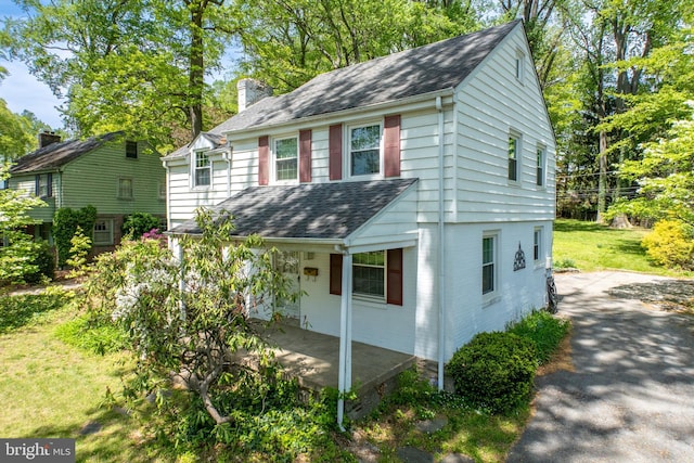 view of front of home with a porch, a shingled roof, and a chimney