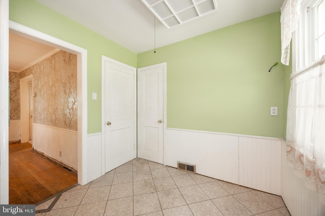 unfurnished room with wainscoting and light tile patterned floors
