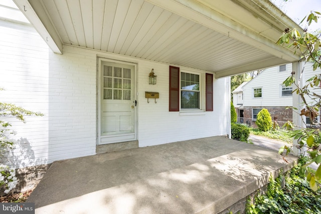 entrance to property with brick siding and a carport