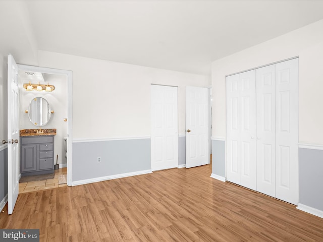 206 Water Fountain Ct Unit 201, Glen Burnie, MD 21060 - unfurnished bedroom with a sink, light wood finished floors, baseboards, and ensuite bathroom