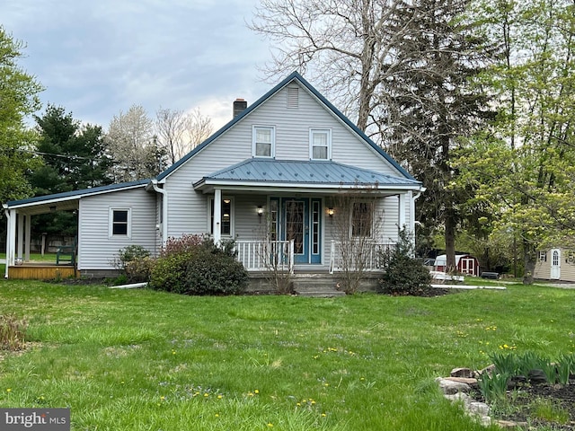 back of property with covered porch, a chimney, a lawn, a shed, and an outbuilding