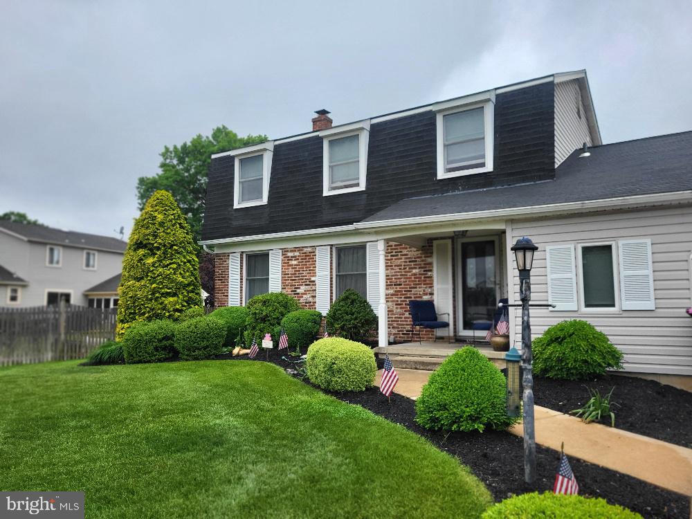 dutch colonial featuring roof with shingles, a chimney, and brick siding