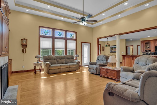 living area featuring a towering ceiling, light wood-style floors, a ceiling fan, decorative columns, and recessed lighting