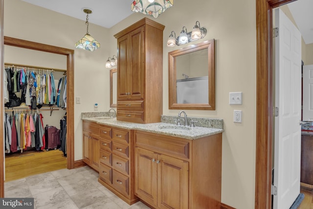 full bathroom featuring double vanity, baseboards, and a spacious closet