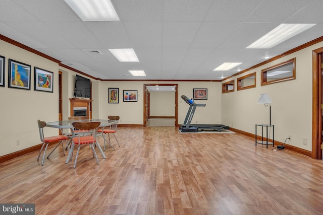exercise area with ornamental molding, wood finished floors, and baseboards