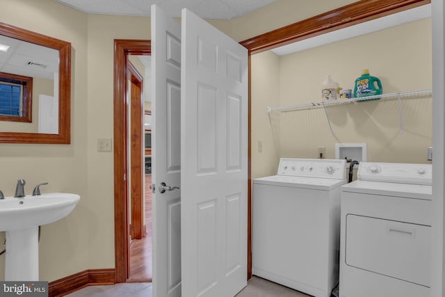 washroom featuring washer and clothes dryer, light tile patterned flooring, and baseboards