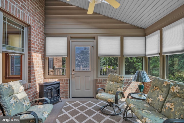 sunroom / solarium featuring a wood stove, lofted ceiling, and carpet