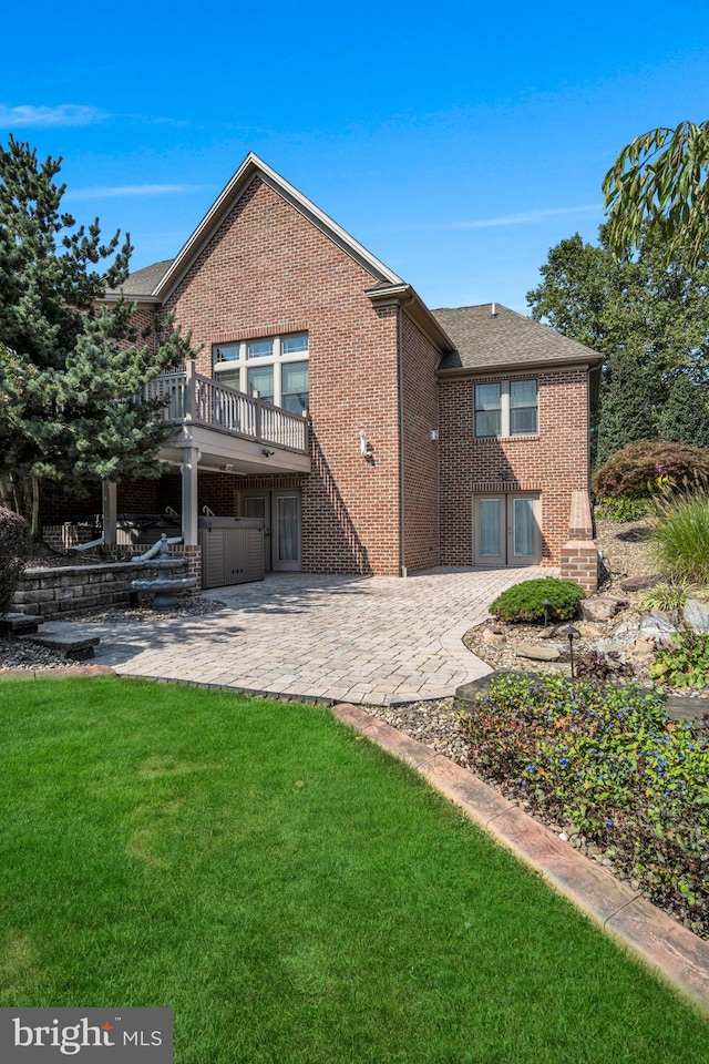 rear view of property with brick siding, a patio, a lawn, and a wooden deck