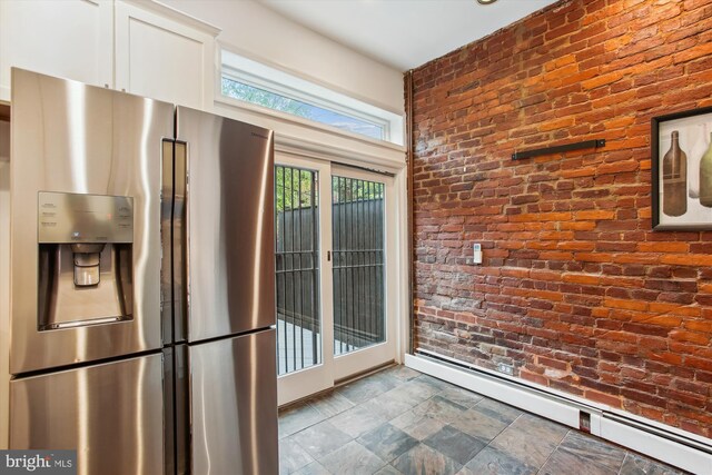 1314 Wallach Pl NW, Washington, DC 20009 - kitchen featuring stainless steel refrigerator with ice dispenser, brick wall, a baseboard radiator, stone finish flooring, and white cabinets