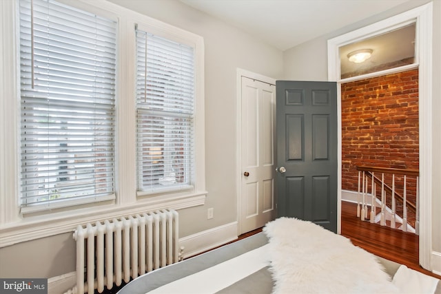 1314 Wallach Pl NW, Washington, DC 20009 - bedroom with radiator heating unit, brick wall, wood finished floors, baseboards, and a closet