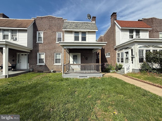 view of front facade with a front lawn, brick siding, covered porch, and cooling unit