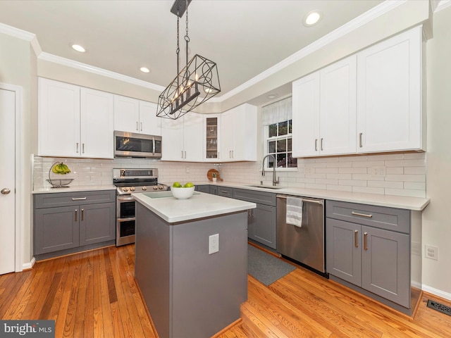 9034 Allington Manor Cir W, Frederick, MD 21703 - kitchen featuring stainless steel appliances, a sink, gray cabinets, ornamental molding, and light wood-type flooring