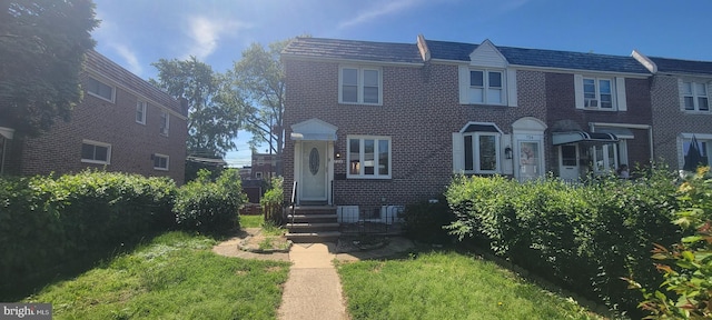 view of front of property with brick siding, entry steps, and a front lawn