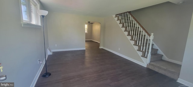 foyer entrance featuring stairs, wood finished floors, baseboards, and arched walkways