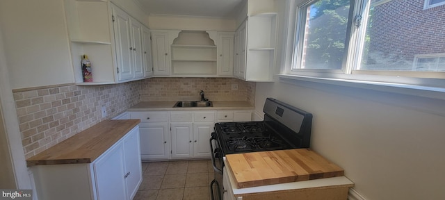 kitchen with wooden counters, open shelves, stainless steel range with gas stovetop, and a sink