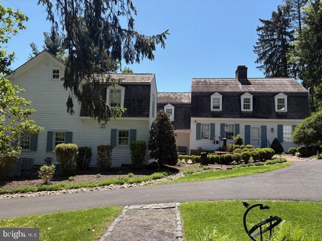 dutch colonial with a chimney and a shingled roof