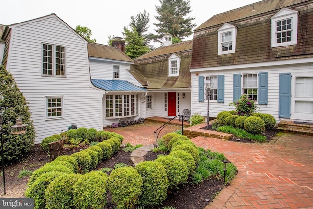 3864 Spring Valley Rd, Doylestown, PA 18902 - view of front of house with a gambrel roof, a chimney, a patio area, and a standing seam roof