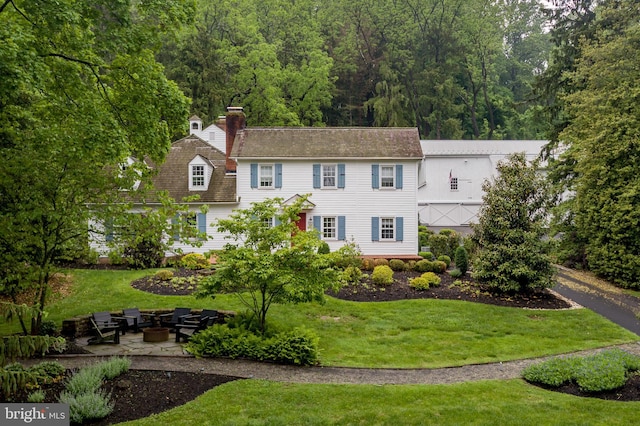 3864 Spring Valley Rd, Doylestown, PA 18902 - colonial-style house featuring a fire pit, a front yard, a chimney, a patio, and a forest view