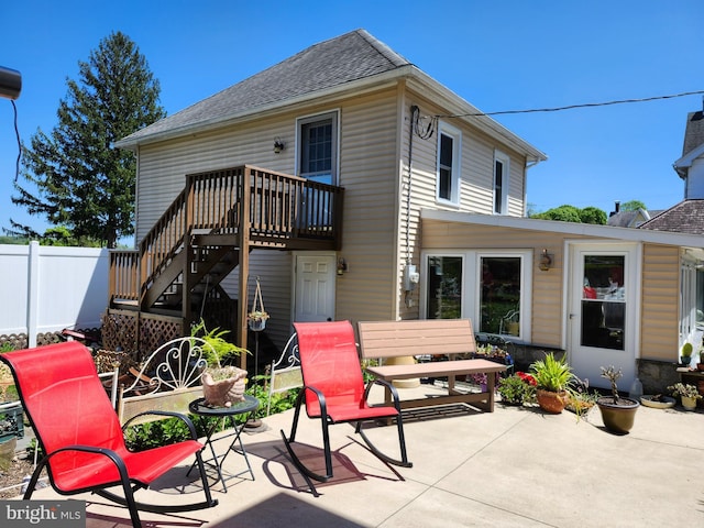 rear view of house with a patio area, fence, roof with shingles, and stairway